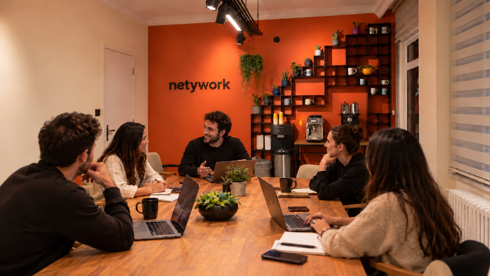 Netywork topluluk alanı — Kadıköy, İstanbul: uzun ahşap masanın çevresinde çalışan ve konuşan altı kişi